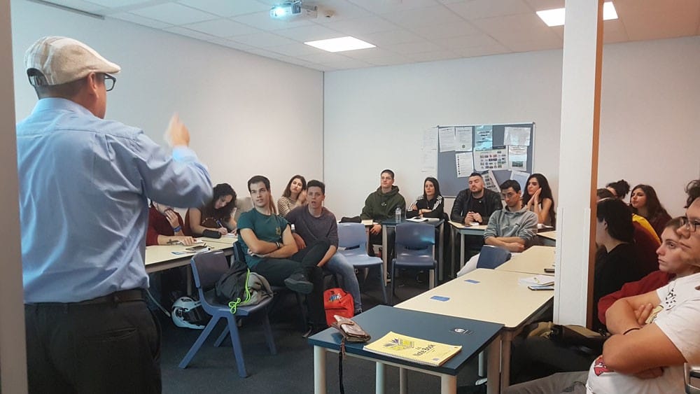 Trabajar en Australia grupo de jóvenes sentados en una clase y un señor explicándoles algo